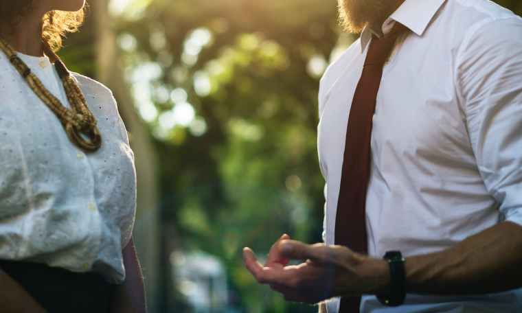 man wearing white shirt holding out hand in front of woman in white lace top